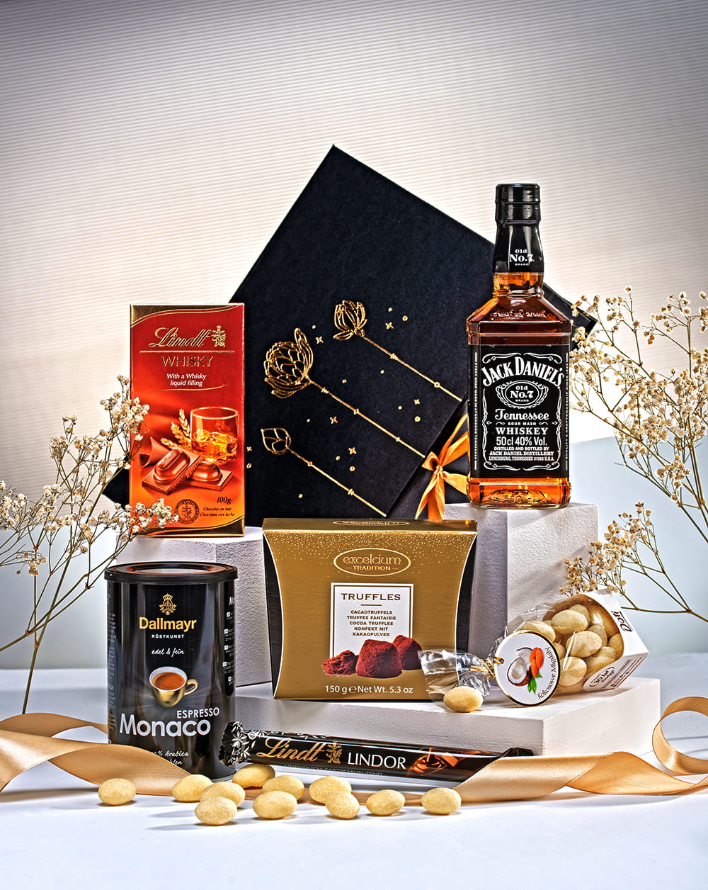 Ekskluzywny kosz prezentowy w czarnym pudełku ze złotą kokardą, z whiskey Jack Daniel's, kawą Lavazza i czekoladami Lindt.