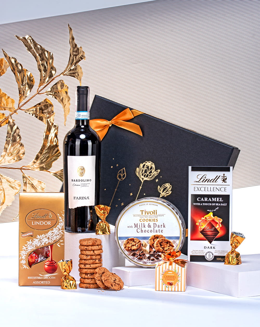 Luksusowe czarne pudełko prezentowe z winem Farina, pralinami Lindt, czekoladą i ciasteczkami.