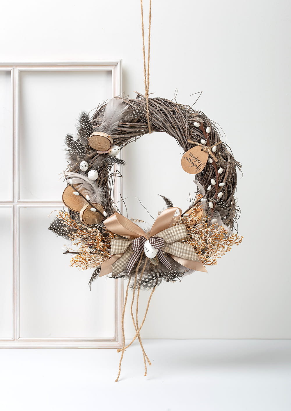 Naturalny ręcznie robiony wianek wielkanocny z bazi, piórkami i jajeczkami w beżowych barwach.