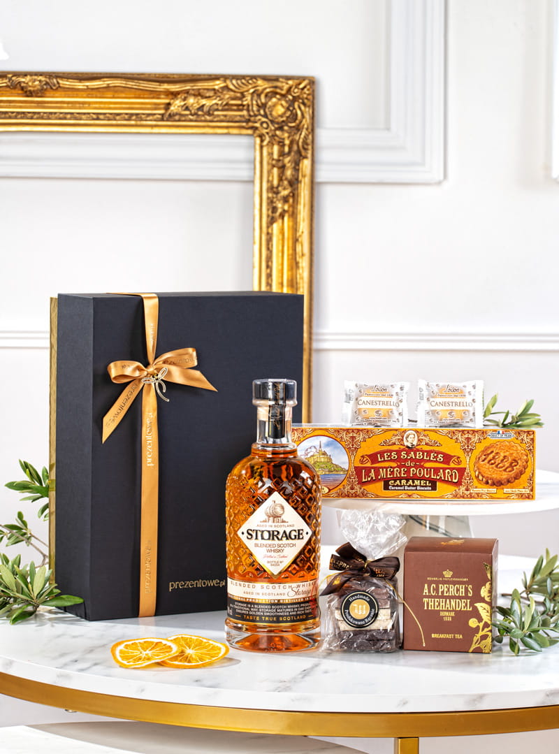 Elegancki złoty zestaw prezentowy z whisky Storage, herbatą Perch's, czekoladkami Wierzynek w luksusowym opakowaniu.
