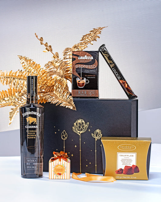 Luksusowy zestaw prezentowy dla mężczyzny w otwartym czarnym pudełku z wódką Czarna Żubrówka, kawą Lavazza i pralinami.