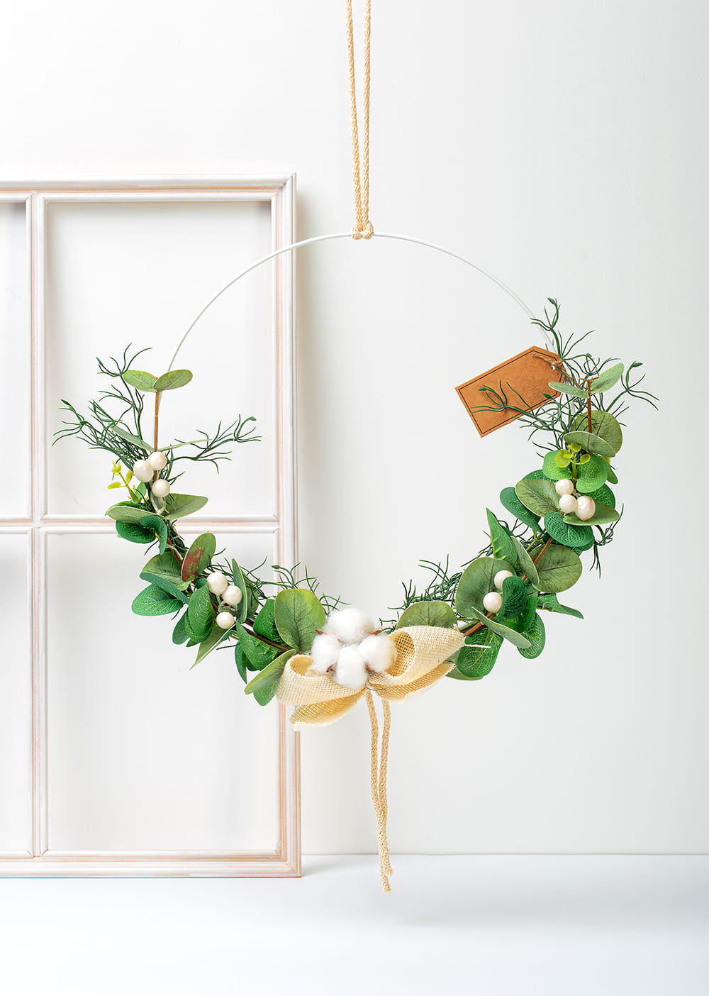 Urokliwy wianek boho z eukaliptusem i puszystym kwiatem bawełny, wiszący na drzwiach.