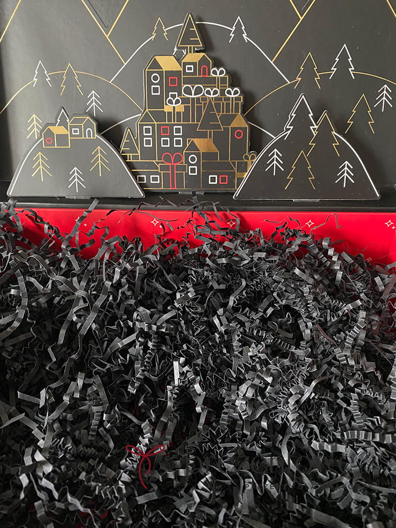 Puszysta góra ekologicznych wiórków papierowych w kolorze czarny mat, używana jako elegancki wypełniacz prezentowy.