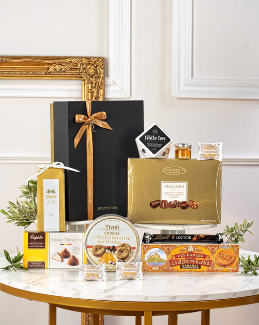 Ekskluzywny zestaw prezentowy w czarno-złotym pudełku z złotą wstążką, z pralinami Lindt, truflami Cupido i francuskim miodem Alain Milliat.