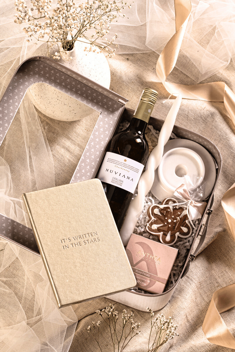 Elegancki zestaw prezentowy z winem Nuviana Chardonnay, herbatą i złotym notesem, w kremowym pudełku-walizce z okienkiem.
