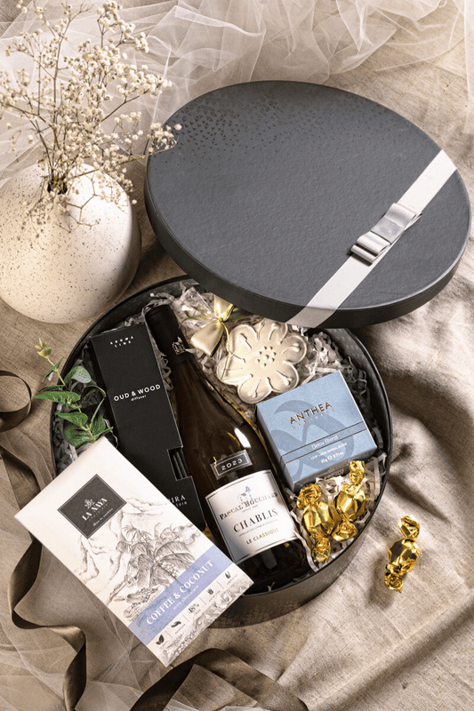 Ekskluzywny box prezentowy z winem Chablis, dyfuzorem zapachowym i ręcznie robioną czekoladą, w czarnym pudełku z szarą kokardą.