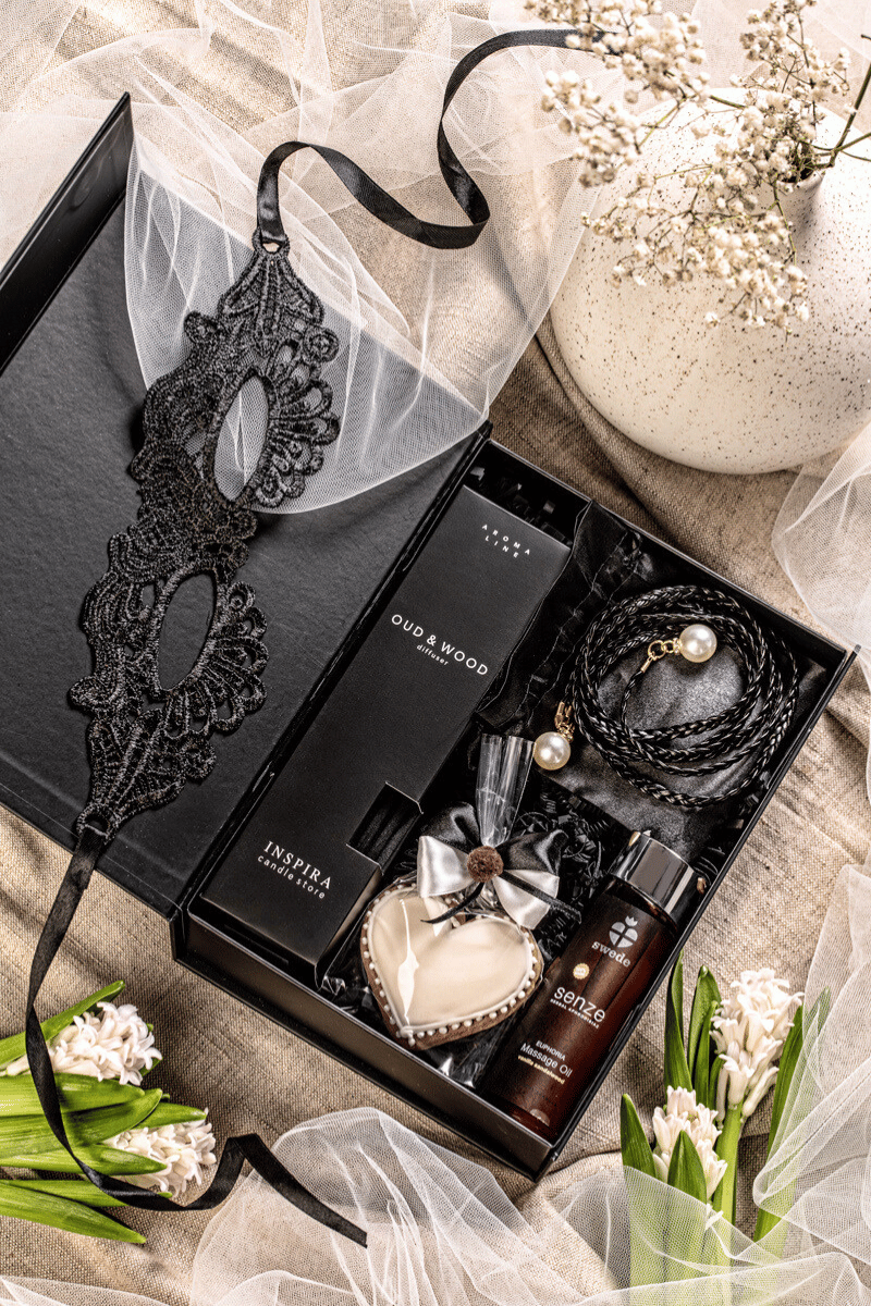 Zmysłowy zestaw prezentowy dla dwojga z dyfuzorem sandałowym, olejkiem do masażu i koronkową maską w eleganckim czarnym pudełku.