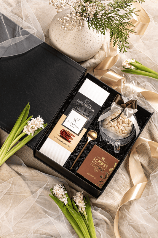 Ekskluzywny zestaw herbaciany w eleganckim czarnym pudełku, z filiżanką, herbatą A.C. Perch's, czekoladą Karmello i migdałowymi karmelkami.