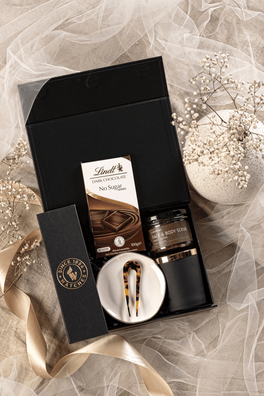 Luksusowy zestaw prezentowy dla kobiety w otwartym czarnym pudełku z kawowym peelingiem, świecą sojową i podstawką.