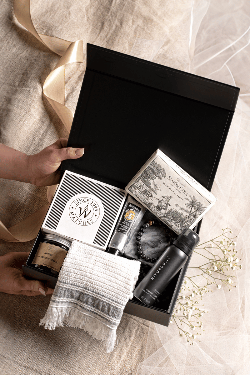 Luksusowy zestaw SPA dla mężczyzny w otwartym czarnym pudełku z satynową kokardą, krem Bullfrog i żelem Rituals.