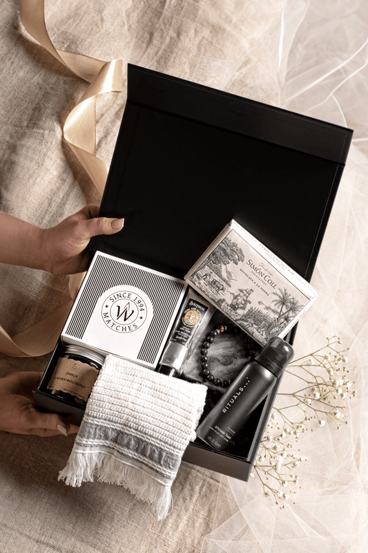 Luksusowy zestaw SPA dla mężczyzny w otwartym czarnym pudełku z satynową kokardą, krem Bullfrog i żelem Rituals.