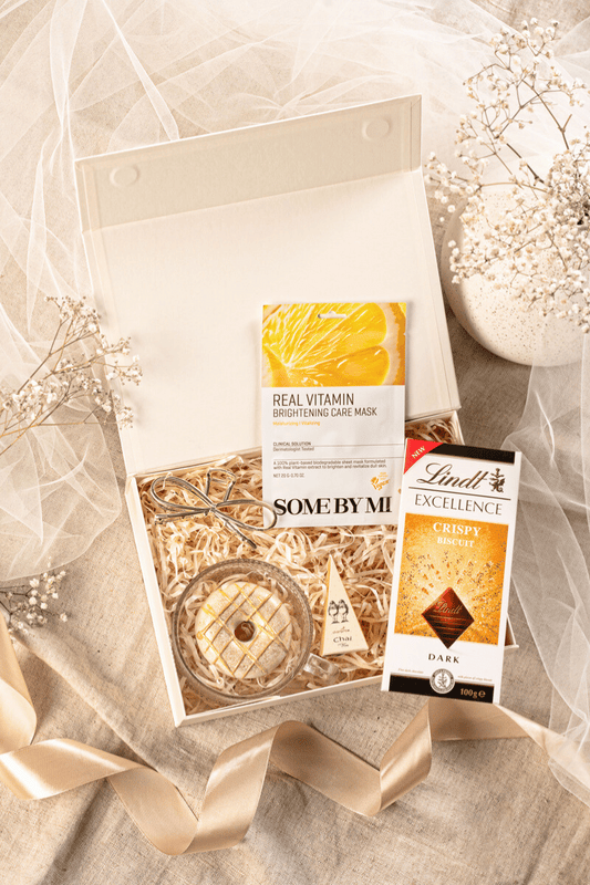 Zestaw podarunkowy dla kobiety w beżowym pudełku, z elegancką filiżanką, herbatą Charbrew, mydełkiem pistacjowym i czekoladą Lindt.