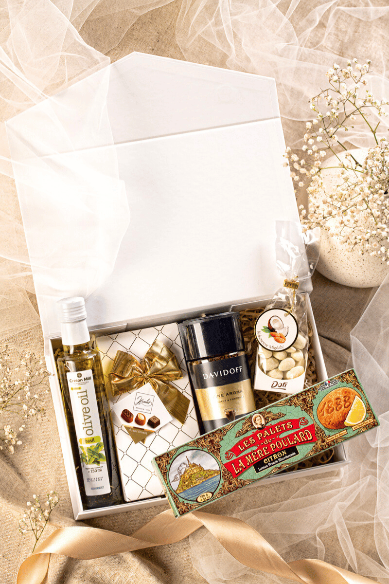Elegancki zestaw prezentowy z kawą Davidoff, belgijskimi pralinami Hamlet i francuskimi ciastkami maślanymi w białym pudełku.